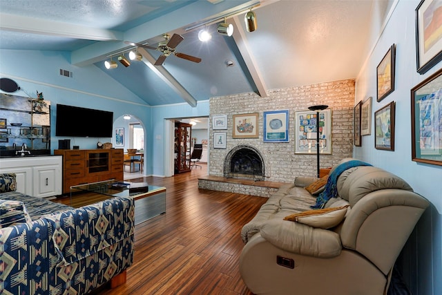 living room featuring hardwood / wood-style flooring, ceiling fan, a fireplace, vaulted ceiling with beams, and a textured ceiling