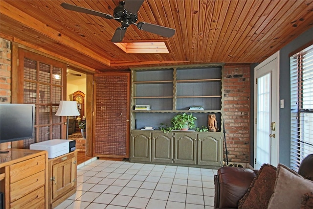 interior space featuring ceiling fan, a skylight, and wood ceiling