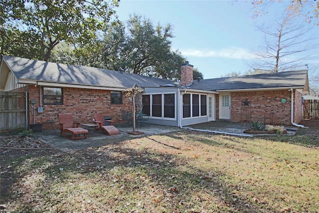 rear view of house featuring a sunroom, a lawn, and a patio