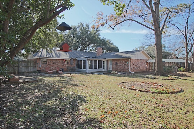 rear view of property featuring a sunroom and a lawn