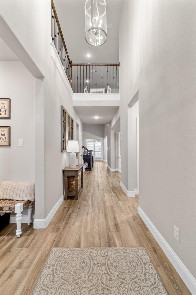 entrance foyer featuring light hardwood / wood-style floors, a high ceiling, and a notable chandelier