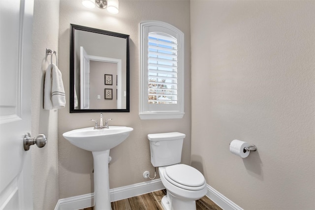 bathroom with toilet, wood-type flooring, and sink