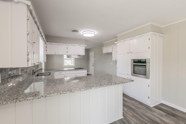 kitchen featuring light stone countertops, white cabinetry, sink, kitchen peninsula, and oven