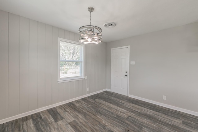 spare room with dark hardwood / wood-style flooring and a chandelier