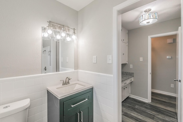 bathroom with wood-type flooring, tile walls, toilet, and vanity