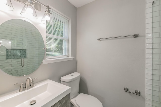 bathroom featuring toilet, a wealth of natural light, an enclosed shower, and vanity