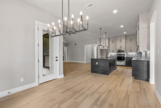 unfurnished bedroom featuring a barn door, carpet floors, a raised ceiling, ensuite bath, and ceiling fan with notable chandelier