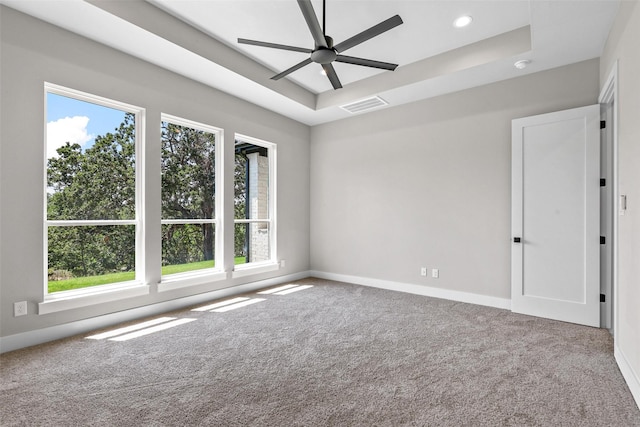 carpeted empty room featuring a raised ceiling and ceiling fan