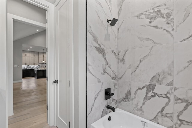 bathroom with decorative backsplash, hardwood / wood-style flooring, and shower / washtub combination