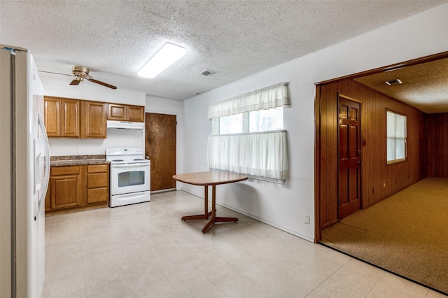 kitchen featuring ceiling fan, wood walls, white appliances, and a textured ceiling