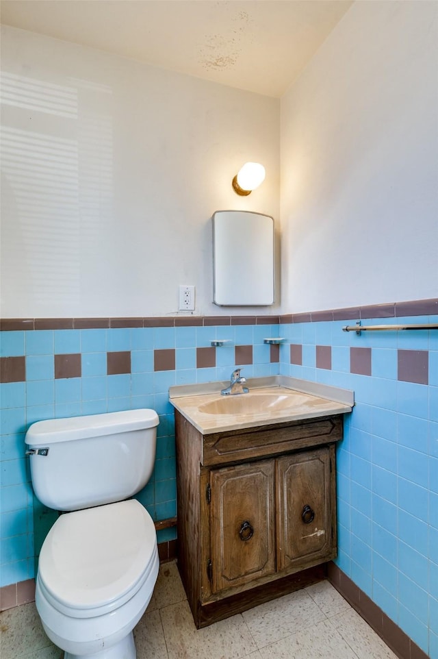 bathroom with toilet, vanity, and tile walls