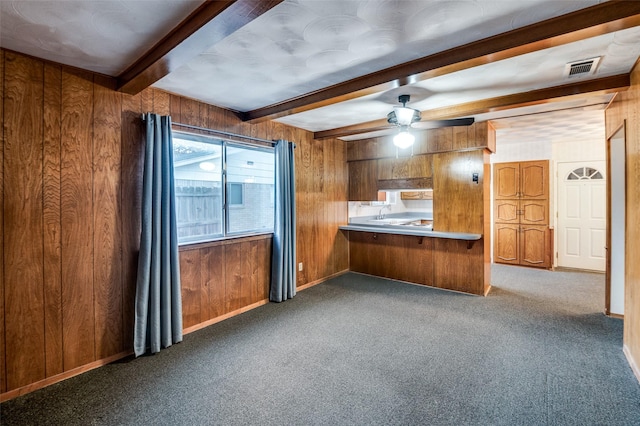 kitchen with dark colored carpet, kitchen peninsula, wood walls, and ceiling fan