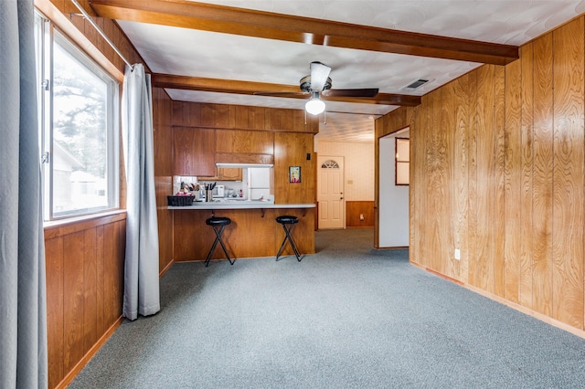 kitchen featuring wood walls, light carpet, kitchen peninsula, and ceiling fan