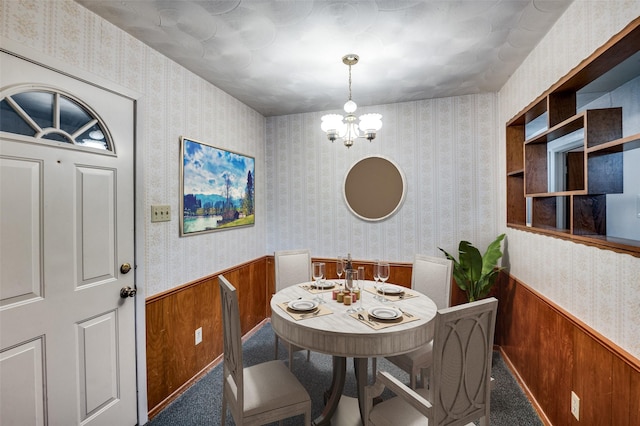 carpeted dining room with a notable chandelier and wooden walls