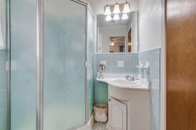 bathroom with a shower with shower door, vanity, tile walls, and ceiling fan