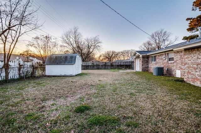 yard at dusk with central AC and a shed