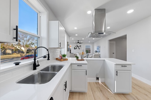 kitchen featuring ceiling fan, white cabinets, sink, and island range hood