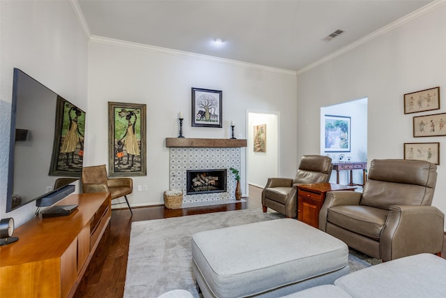 living room with dark hardwood / wood-style flooring, ornamental molding, and a tiled fireplace