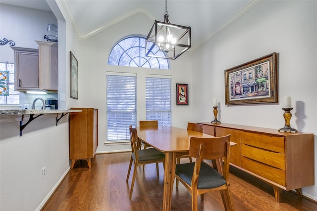 dining space featuring a notable chandelier, dark wood-type flooring, lofted ceiling, ornamental molding, and sink