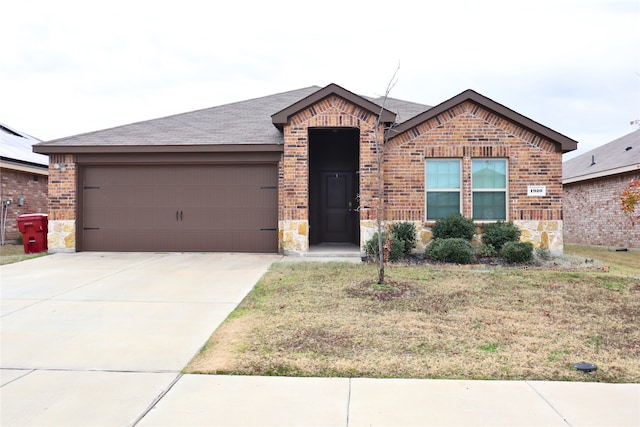 view of front facade with brick siding, roof with shingles, concrete driveway, stone siding, and a front lawn