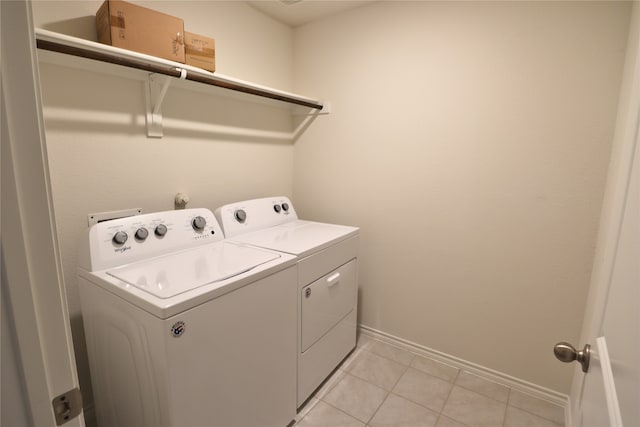 washroom with laundry area, light tile patterned floors, baseboards, and washer and clothes dryer