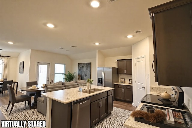 kitchen with stainless steel appliances, visible vents, open floor plan, light countertops, and an island with sink