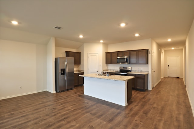 kitchen with dark wood finished floors, stainless steel appliances, visible vents, a sink, and an island with sink