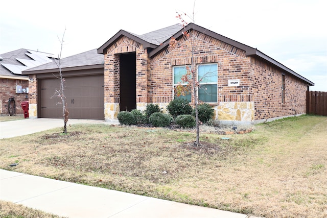 view of front of home featuring an attached garage, brick siding, driveway, stone siding, and a front yard