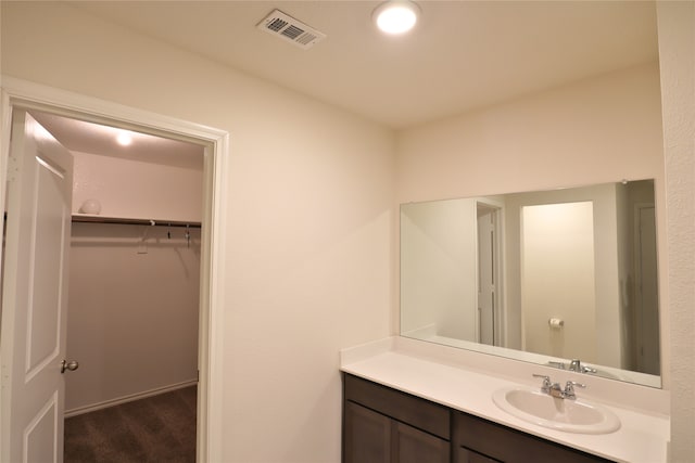 bathroom featuring vanity, a walk in closet, and visible vents