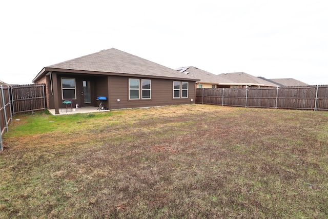 back of property featuring a patio, a yard, and a fenced backyard