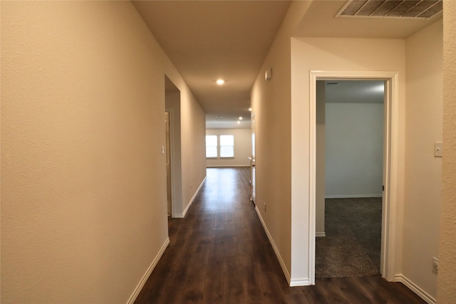 corridor with baseboards, visible vents, and dark wood-style flooring