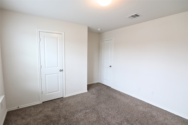 unfurnished bedroom with visible vents, baseboards, and dark colored carpet