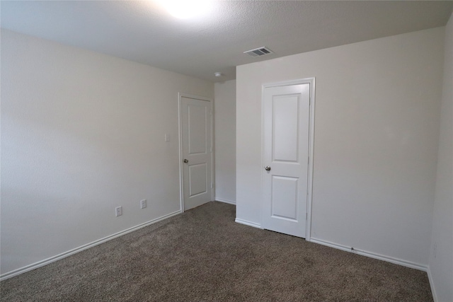 unfurnished room featuring dark carpet, visible vents, and baseboards