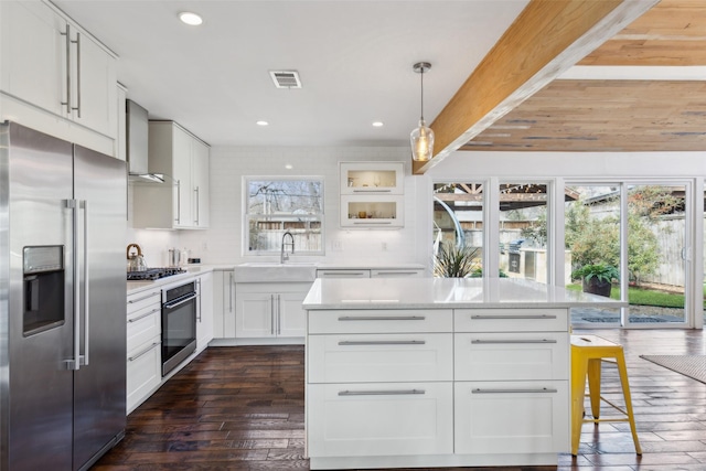 kitchen featuring white cabinets, a kitchen bar, decorative light fixtures, stainless steel appliances, and sink