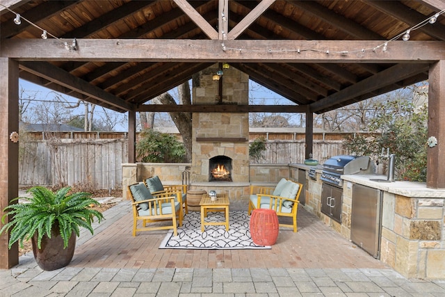 view of patio / terrace with an outdoor kitchen, a gazebo, grilling area, and an outdoor stone fireplace