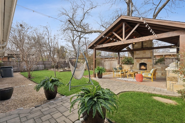 view of patio / terrace featuring central air condition unit, a gazebo, and an outdoor stone fireplace