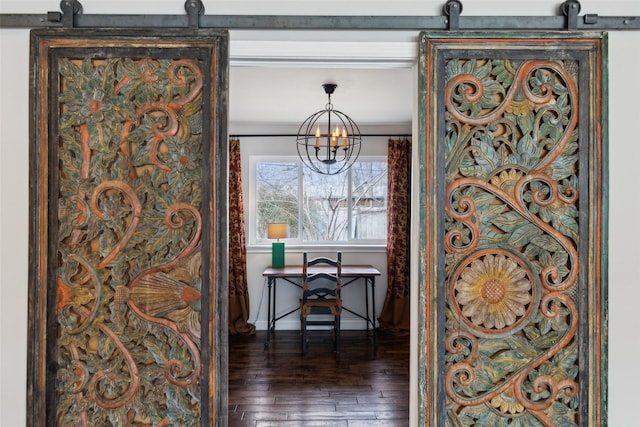 hallway featuring dark wood-type flooring, a chandelier, ornamental molding, and a barn door