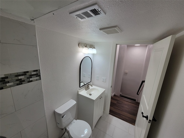 bathroom with a textured ceiling, tile patterned floors, vanity, and toilet