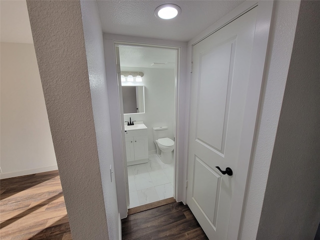 corridor with dark hardwood / wood-style flooring, sink, and a textured ceiling