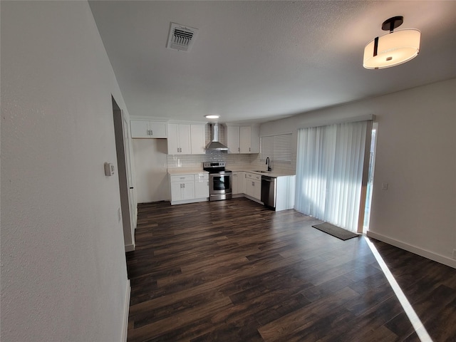 kitchen featuring backsplash, white cabinetry, dark wood-type flooring, stainless steel appliances, and wall chimney exhaust hood