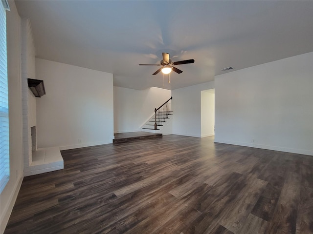 unfurnished living room featuring dark wood-type flooring and ceiling fan