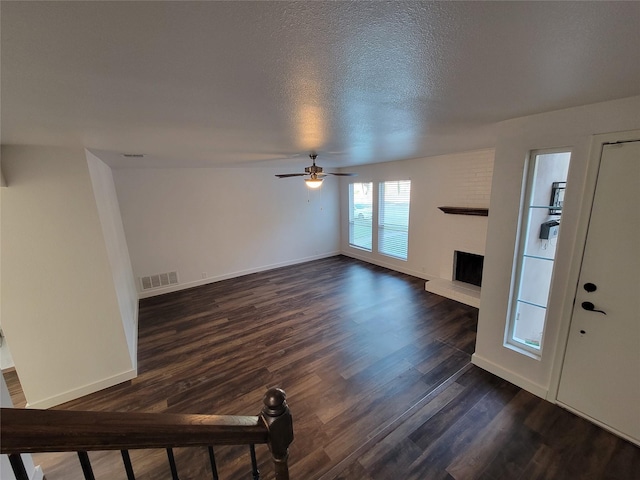 unfurnished living room with ceiling fan, dark wood-type flooring, and a textured ceiling