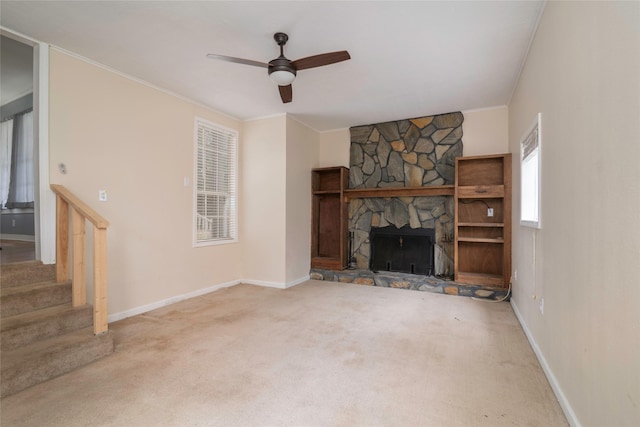 unfurnished living room with carpet floors, ceiling fan, a fireplace, and crown molding