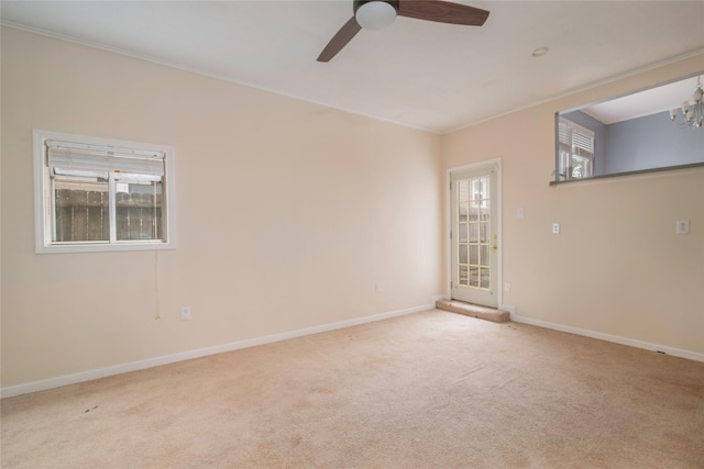 empty room featuring ceiling fan with notable chandelier, light carpet, and a healthy amount of sunlight