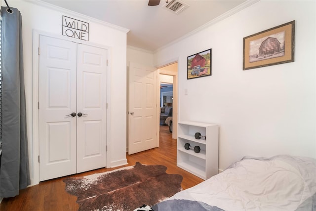 bedroom with ceiling fan, wood-type flooring, a closet, and crown molding