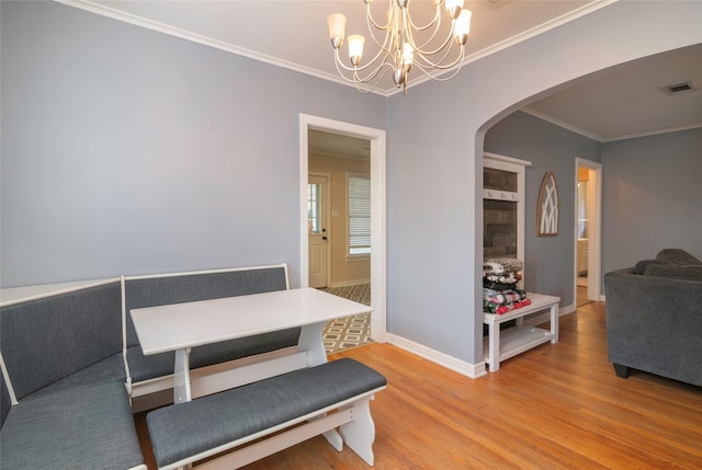 dining space featuring hardwood / wood-style floors, ornamental molding, and an inviting chandelier