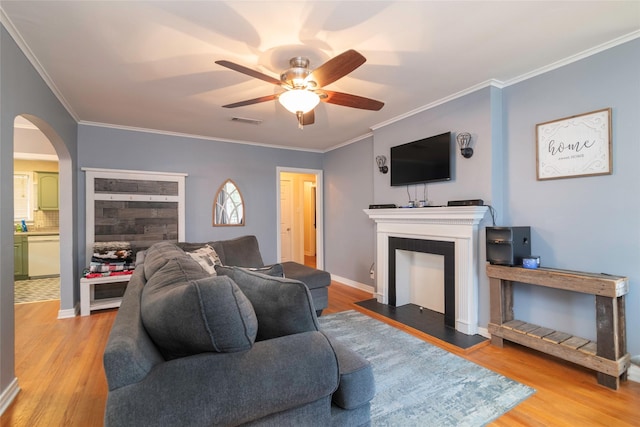 living room featuring ceiling fan, wood-type flooring, and crown molding