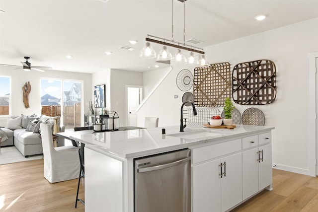 kitchen featuring sink, light wood-type flooring, stainless steel dishwasher, white cabinets, and an island with sink