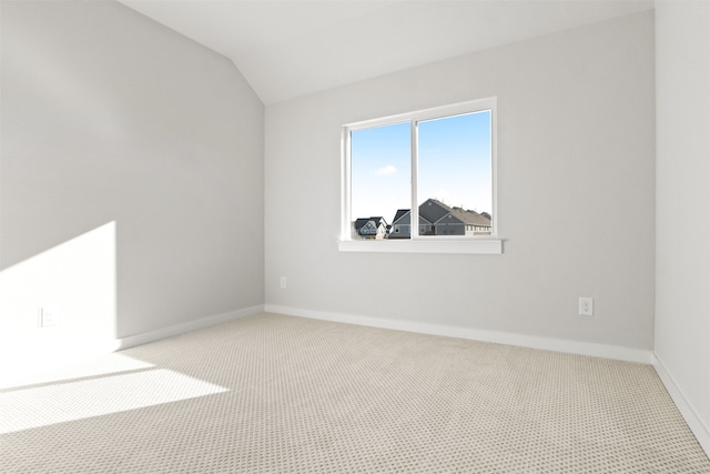 carpeted spare room with vaulted ceiling