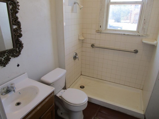 bathroom with toilet, vanity, and a tile shower